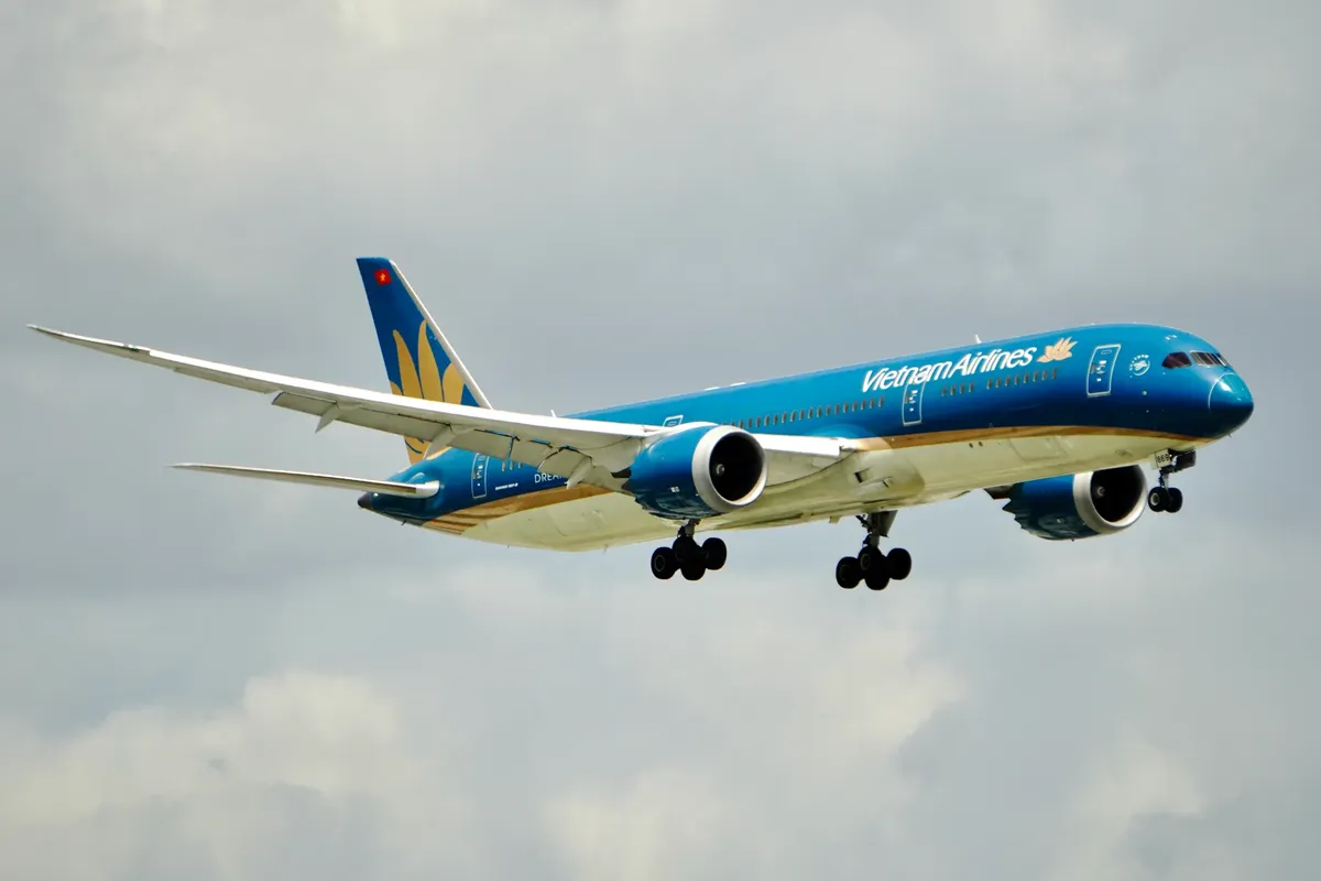 Vietnam Airlines Boeing 787 Dreamliner flying against a cloudy sky, showcasing air travel elegance.