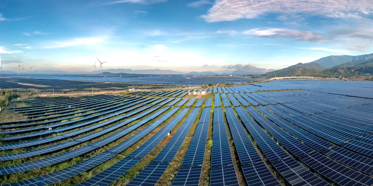 廣闊的太陽電廠與風力發電機組在日出時段發電，展現可再生能源的永續技術
