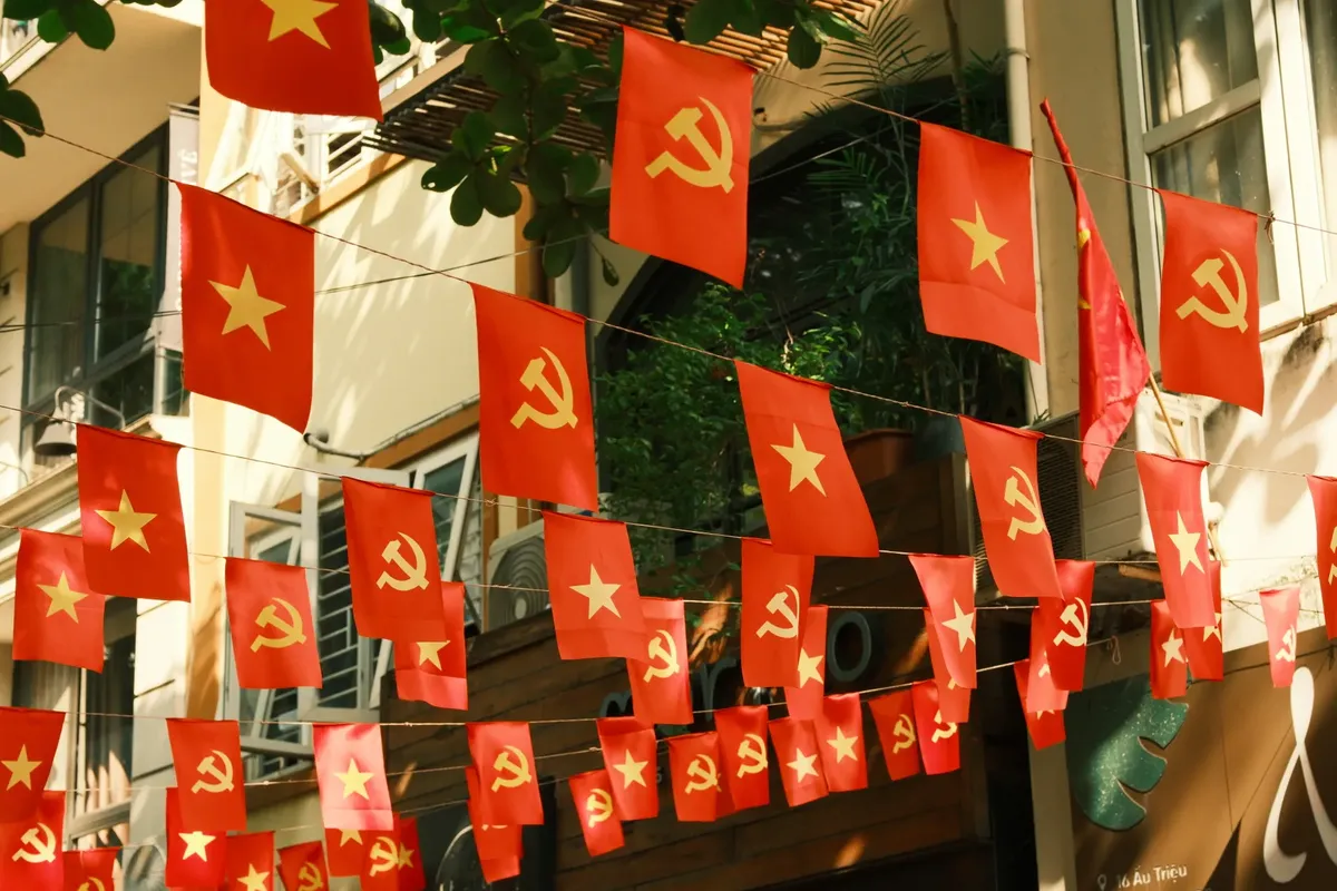 Red flags with communist symbols and yellow stars hanging in a city street.