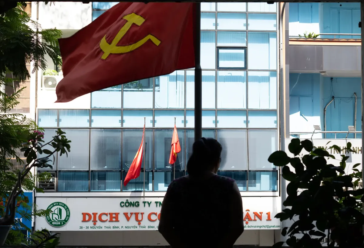 Silhouette of a woman in Ho Chi Minh City with communist flag and urban backdrop.