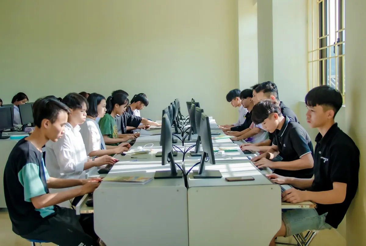教室裡一群學生專注於電腦螢幕，促進數位教育