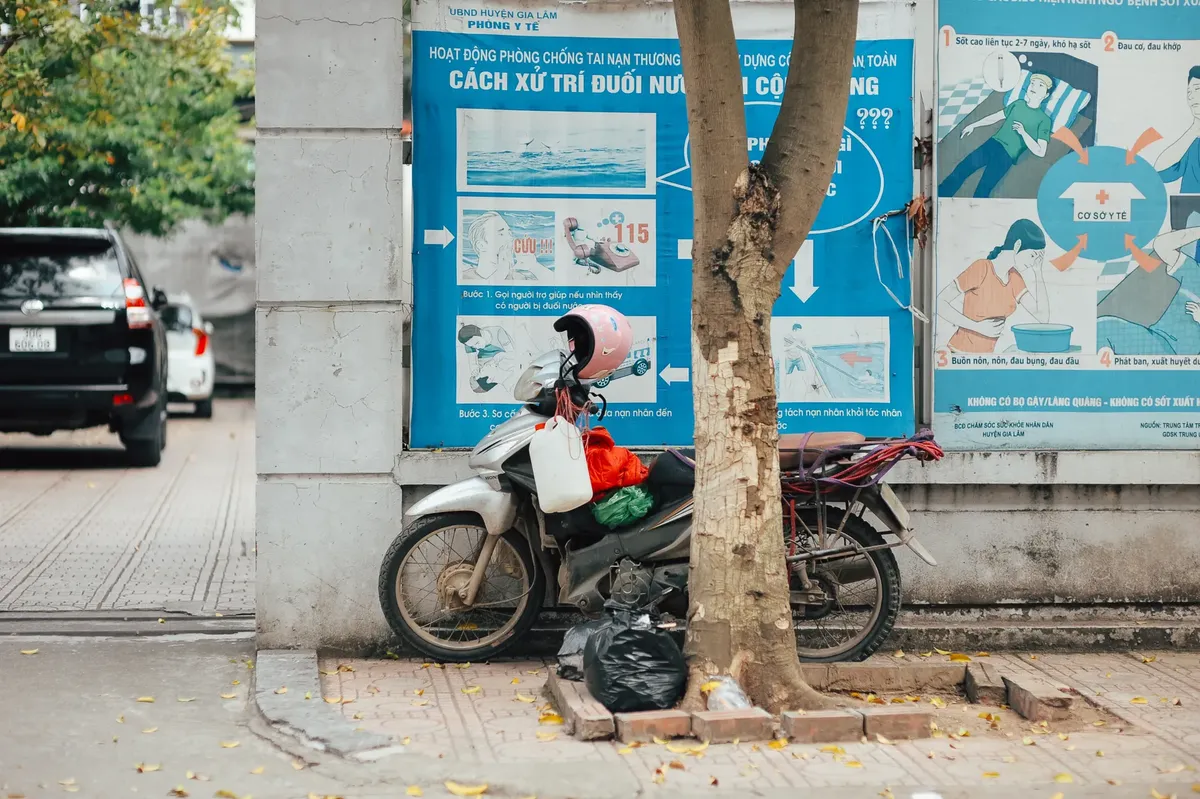 Motorbike with pink helmet parked against city wall featuring informational health posters.