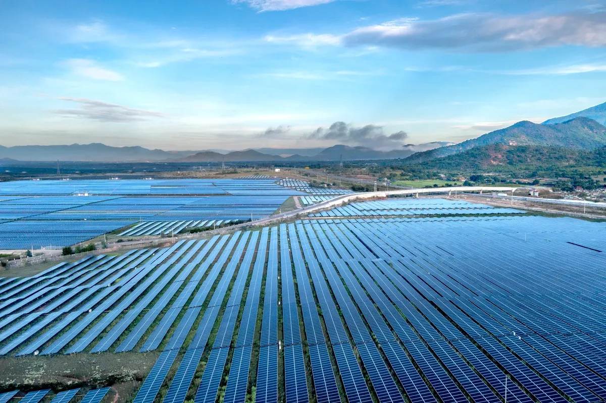 Aerial view of a sprawling solar farm under a vibrant sky in Vietnam's Ninh Thuan during daytime.