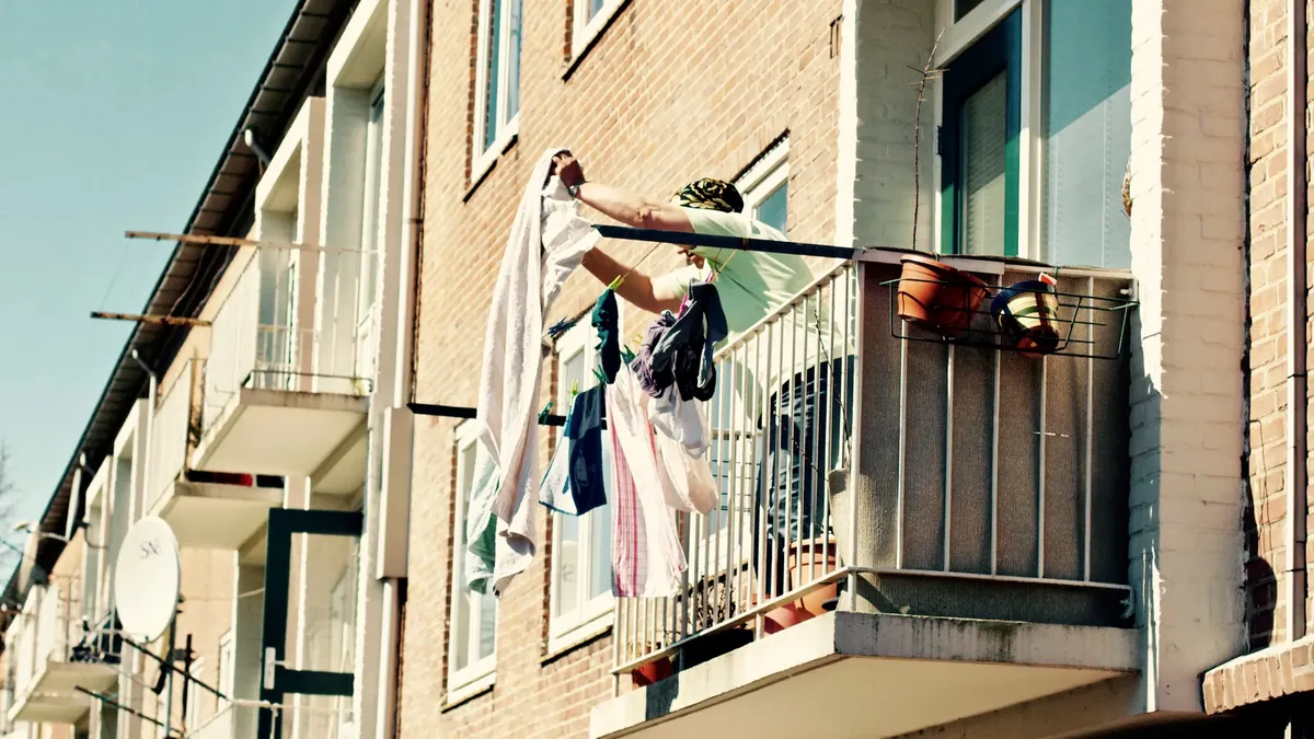 A person hangs laundry on a sunny balcony in Amersfoort, Netherlands, showcasing urban lifestyle.