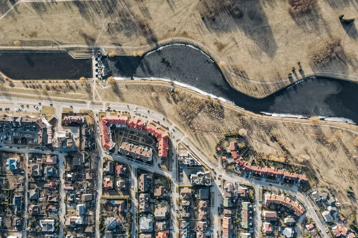 High-altitude view capturing suburban houses, roads, river, and grassland.