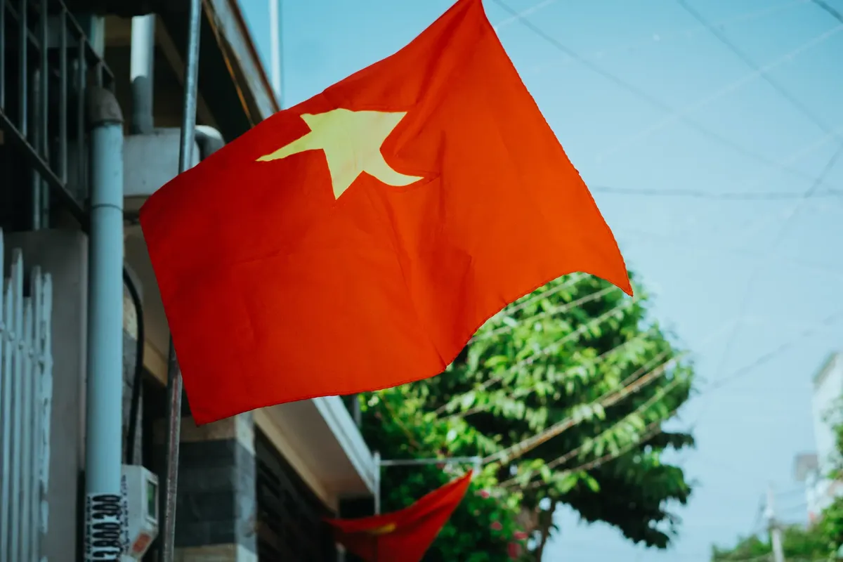 Close-up of the Vietnam flag waving against a clear blue sky in a city street, showcasing vibrant colors.
